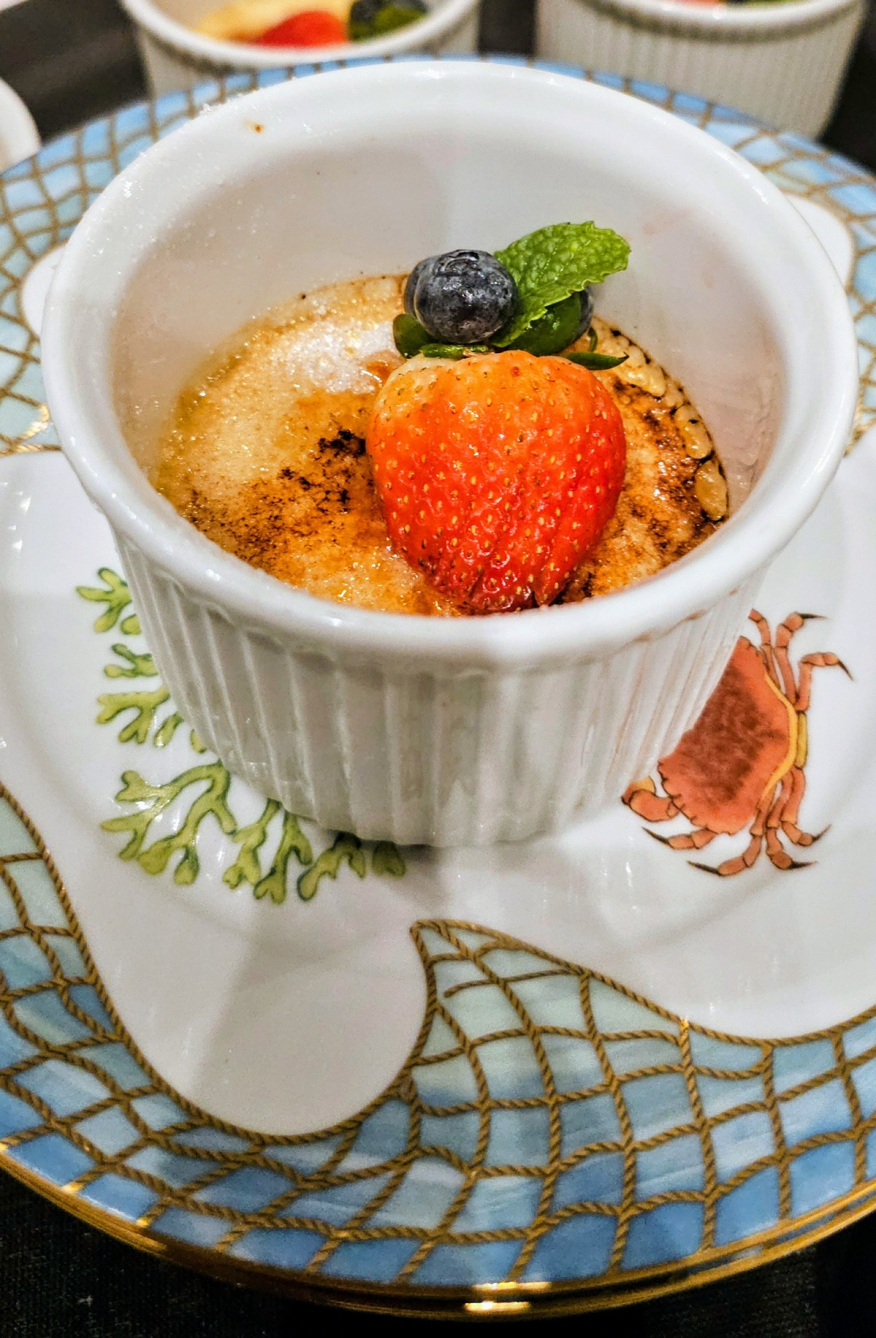 Dessert presented in a white ramekin with a strawberry and blueberry on top